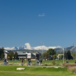 Students walk on the West Lawn of the Colorado State University in the with snow on Longs Peak in the background.